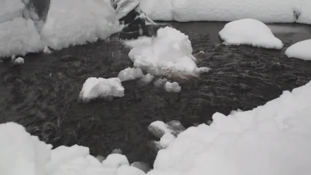 Passos de homem através do riacho. Inverno, há muita neve e nevascas ao redor — Vídeo de Stock