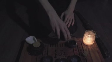Dizlerinin üzerinde oturan adam kendine yeşil çay dolduruyor. Erkeğin yanında katana kılıcı yatıyor.