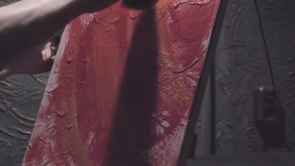 Man hand applicerar färg med hjälp av en svamp på en duk stående på ett staffli — Stockvideo