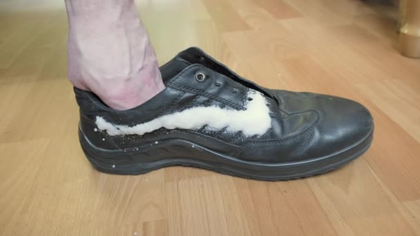 Мужчина распыляет крем на обувь к осеннему сезону и вытирает мягкой тканью — стоковое видео