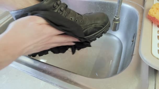 Der Mensch wäscht seine Schuhe für die kalte Jahreszeit in einer eisernen Spüle. Konzept der sorgfältigen Schuhpflege — Stockvideo