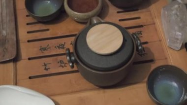 Çay tahtası boyunca kamera hareket ediyor. Yakın çekim. Çayı kil heykelciğin üzerine döker.