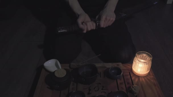 Chá e canecas com bebida. Homem tira samurai espada katana de bainha — Vídeo de Stock