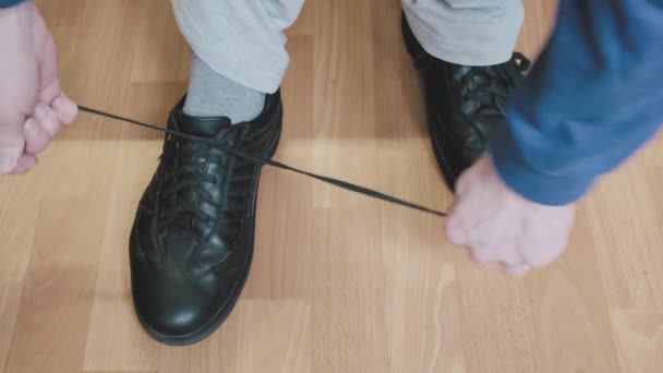 Man in blauwe jas en witte broek stropdassen veters van zijn zwarte schoenen — Stockvideo