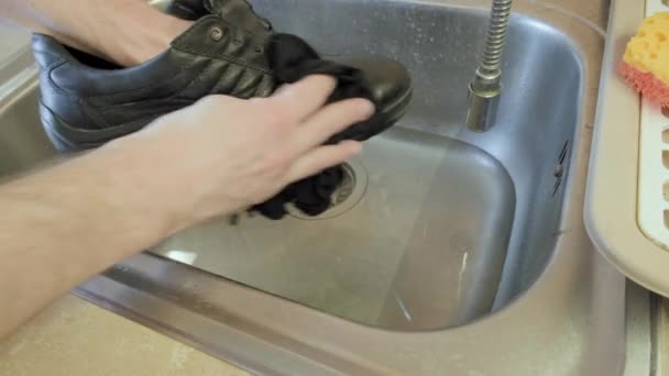 Man voorzichtig wast zijn schoenen voor de herfst voorjaar seizoen in een ijzeren gootsteen — Stockvideo