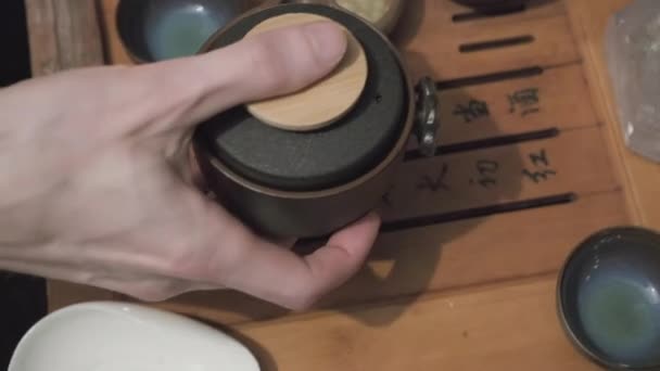 Plateau à thé, prise de vue rapprochée. Homme main verse oolong vert dans des tasses d'argile — Video