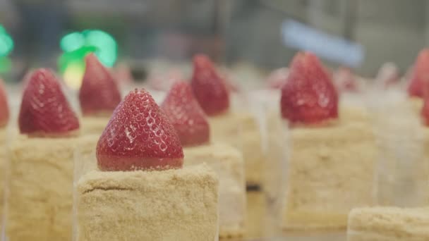 No balcão de uma pastelaria há bolos com morangos frescos no topo — Vídeo de Stock