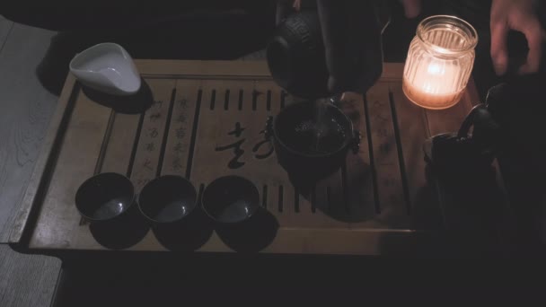 Les cérémonies de maître versent le thé vert dans des tasses. Bouddha figure, bougie sur le plateau de thé — Video