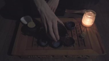 Çay ustası küçük, killi fincanlara çay doldurur. Sonra da kurbağa heykelciğinin üzerine su döker.