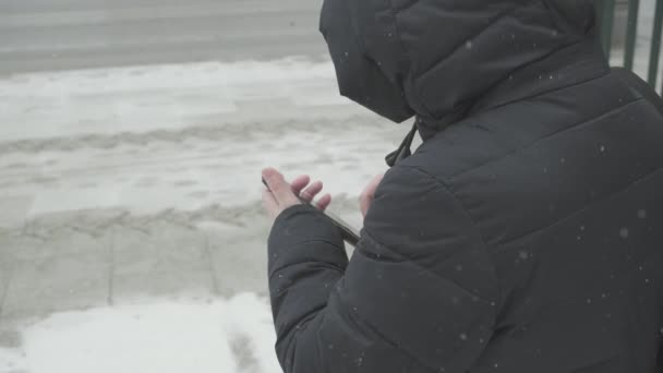 Vallende sneeuw, vrouw in warme jas langs de weg gesprekken taxi door haar telefoon — Stockvideo