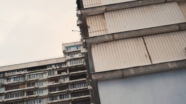 Eski, paslı bir bina. Kamera farklı yönlere döner, sallanan bina