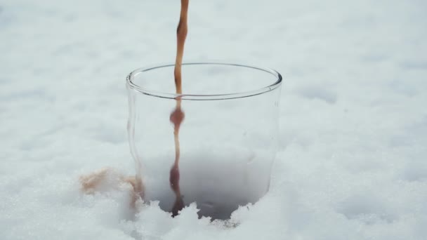 Σκοτεινή, δυνατή μπύρα χύνεται αργά σε ένα ποτήρι που στέκεται στο χιόνι. — Αρχείο Βίντεο