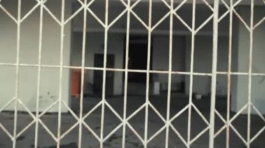 Kamera paslı ızgaraya geçiyor. Sonra eve korkunç, pejmürde bir giriş yaptı.