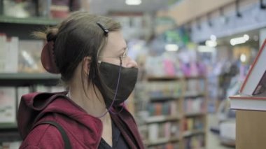 Virüse karşı gözlük ve maske takan kadın kitapçıdan kitap almayı seçti
