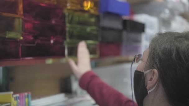 Woman wearing glasses and a mask against the virus buys document pallets — Stock Video