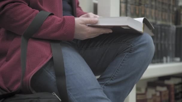 Mujer caucásica en gafas y máscara contra el virus sentado lee libro en la biblioteca — Vídeos de Stock