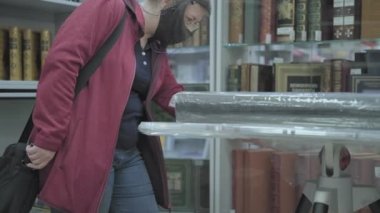 Ciddi bir beyaz kadın gözlük takıyor ve maske takıyor.