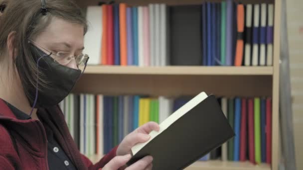 Woman wearing glasses and mask against virus buys in store notebook for notes — Stock Video