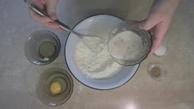 Adam unu çırpmayla karıştırıyor, sonra ekşi ekmek ekliyor ve karıştırmaya devam ediyor.