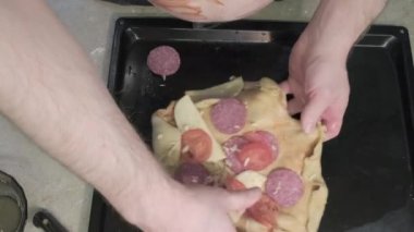 Karnında yazı yazan şişman bir adam pizzayı domates sapıyla süslüyor.