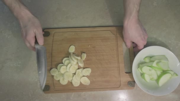 Uomo fette di banana con per insalata di frutta dolce e lo mette nel piatto con le mele — Video Stock