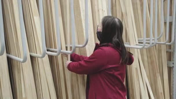 Vrouw in tegen virus masker koopt lange houten planken voor de bouw — Stockvideo