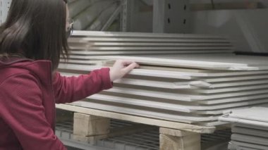 Virüse karşı maskeli bir kadın inşaat malzemeleri mağazasından fiberboard alıyor.