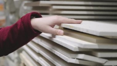 Kadın inşaat malzemeleri dükkanından duvar kaplamaları için fiberboard alıyor. Kapat.
