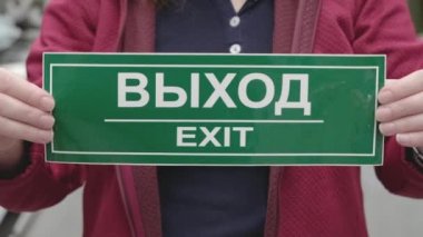 Kadının elinde Rusça ve İngilizce yazılar var. Eller yukarı.
