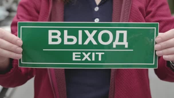 Woman holds sign with inscription exit in Russian and English. Hands close up — Stock Video