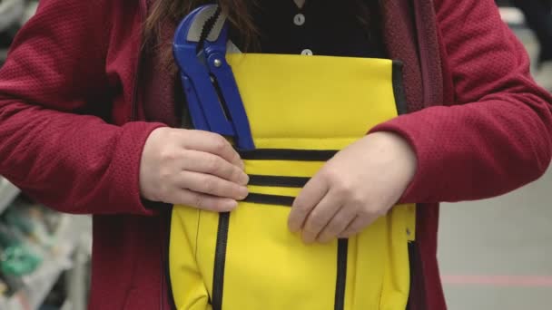 Mulher na loja escolhe saco de ferramentas amarelo resistente. No saco é azul chave ajustável — Vídeo de Stock