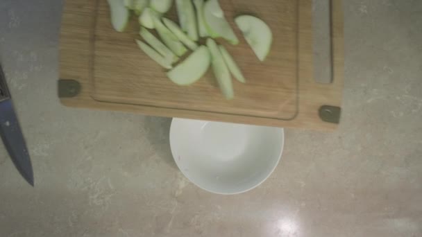 Muž dává jablečné plátky na sladký ovocný salát do talíře. Zavřít — Stock video