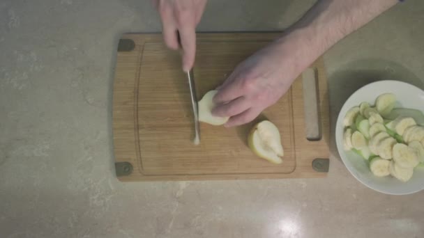 人把一个黄色的梨子切成薄片,做成甜的水果沙拉.健康饮食的概念 — 图库视频影像