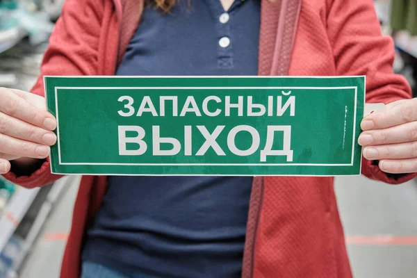 妇女举着一个标有俄罗斯西里尔字母紧急出口的标志。靠近点 — 图库照片