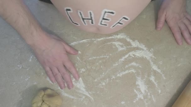 Tlustý muž s nápisem šéfkuchař na břiše hnětá těsto na pečení — Stock video