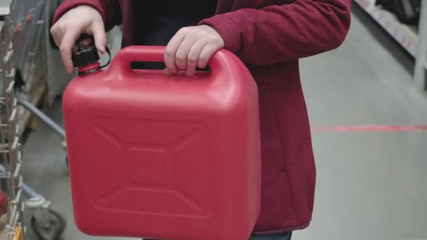 Mulher na loja de estacionamento escolhe para compra grande lata de plástico vermelho sob combustível — Vídeo de Stock