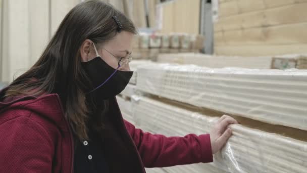 Femme dans le magasin de matériaux de construction choisit de longues lattes en bois à acheter. Gros plan — Video