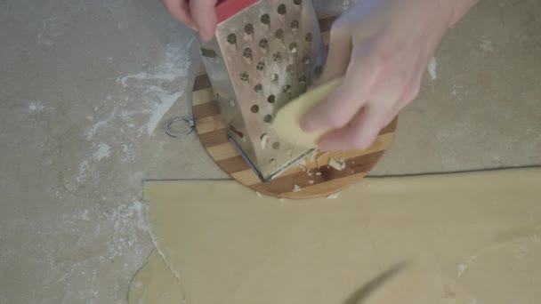 L'uomo strofina il formaggio per riempirsi in gnocchi. Accanto ad esso si trova la pasta rotolata — Video Stock