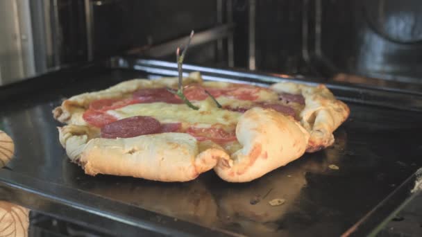 Mans ruka v rukavici vytáhne nevzhlednou, křivý venkovský styl pizzu z trouby — Stock video