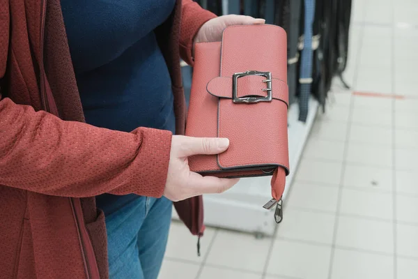 Gravid kvinna i en butik plockar ut röd kopplingspåse för köp. Händerna nära — Stockfoto