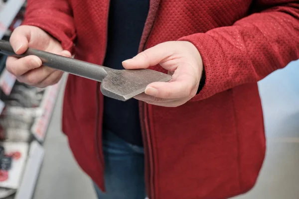 Woman in building materials store chooses for buy wide drill for drilling walls