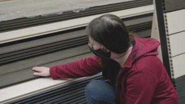 Maskeli kadın mağazada. Duvarlar için panelleri seçiyor. Kapat.