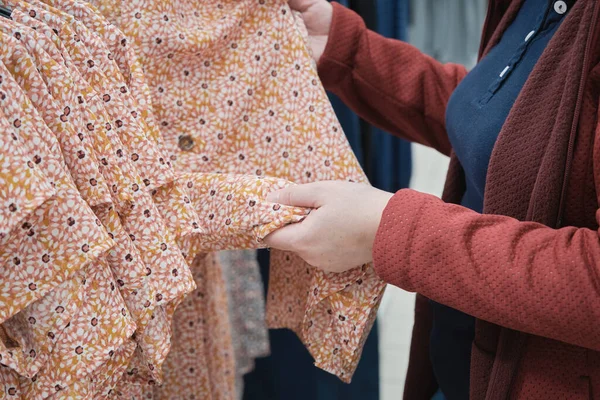 A mulher grávida escolhe um vestido solto em uma flor para comprar. Mãos de perto tiro — Fotografia de Stock