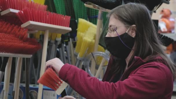 Žena v masce proti viru je v železářství a rozhodne se koupit mop na čištění — Stock video