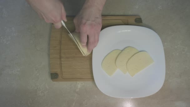 O homem corta queijo com uma faca de lombo. Conceito de cozinha caseira como um hobby — Vídeo de Stock