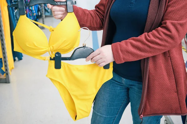 Mulher grávida caucasiana escolhe amarelo brilhante, maiô aberto na loja para comprar — Fotografia de Stock