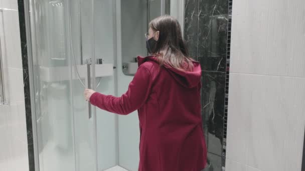 De vrouw in de winkel kiest een douchecabine. Ze draagt een masker tegen het virus. — Stockvideo