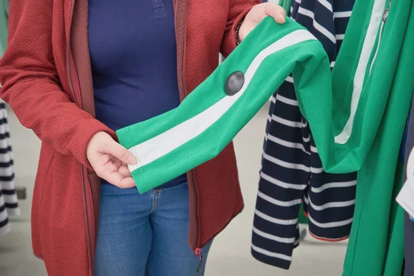 Kobieta w ciąży wybiera luźne zielone spodnie z białymi paskami w sklepie kupić — Zdjęcie stockowe