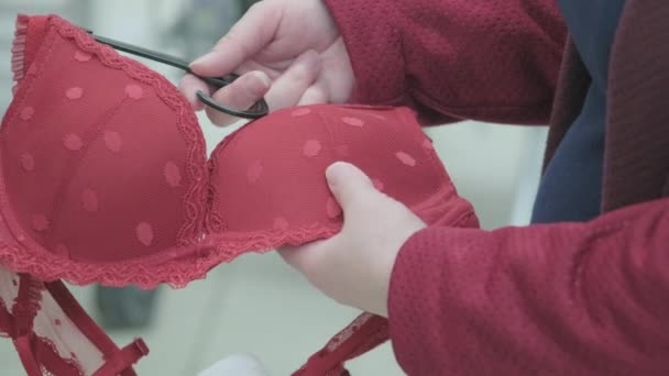 妊婦は衣料品店で大きな赤いブラジャーを選択します。手を閉じるショット — ストック動画