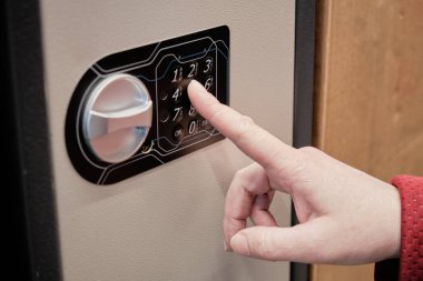 Kadın demir kasanın şifresini çeviriyor. Eller yakın çekim